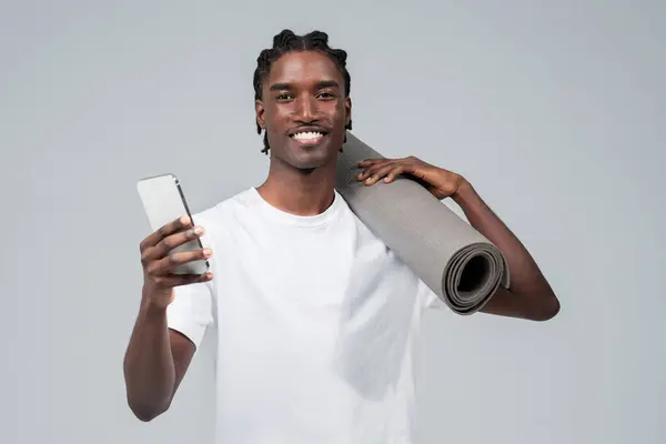 Neşeli Siyah Adam Elinde Yoga Minderi Akıllı Telefon Tutuyor Atletik — Stok fotoğraf