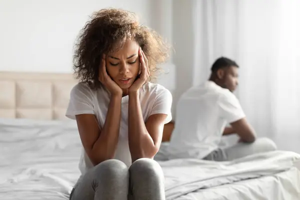 Relationship Crisis Problem. Frustrated African American Millennial Spouses Sitting On Different Sides Of Bed In Bedroom, Sulking After Conflict, Having Disagreements And Issues In Marriage