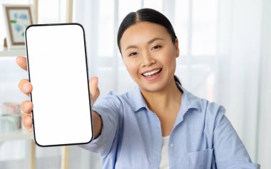 Neşeli Asyalı kadın telefonu elinde tutuyor. Beyaz beyaz ekran fotokopi alanı, ev içi. Mutlu Asyalı kadın güzel mobil uygulama, alışveriş, bankacılık online, web sörfü, kaydırma