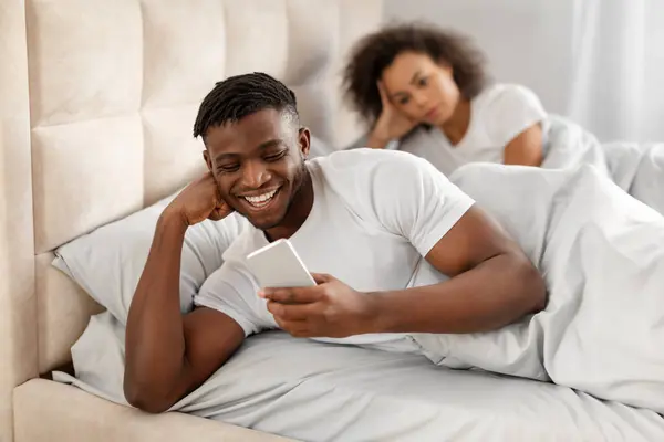 Phubbing Nespokojený Afroameričanka Při Pohledu Přítele Textování Telefonu Posteli Ignorování — Stock fotografie