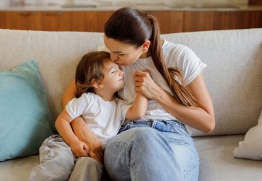 Annesini seven, küçük kızını kucaklayan, koltukta yan yana oturan, mutlu anne ve çocuk evde kaynaşan, anne ve çocuk, birlikte vakit geçiren...