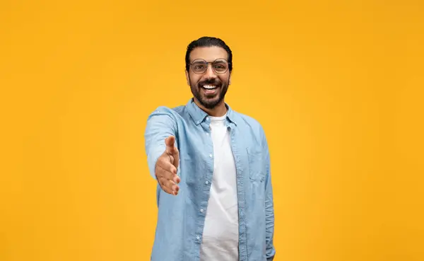 ハンドシェイクのために手を差し伸べ 暖かく微笑み 接続とインタラクションを誘い 陽気な黄色の背景に設定されたアミューズブルな男 ディールジェスチャー — ストック写真