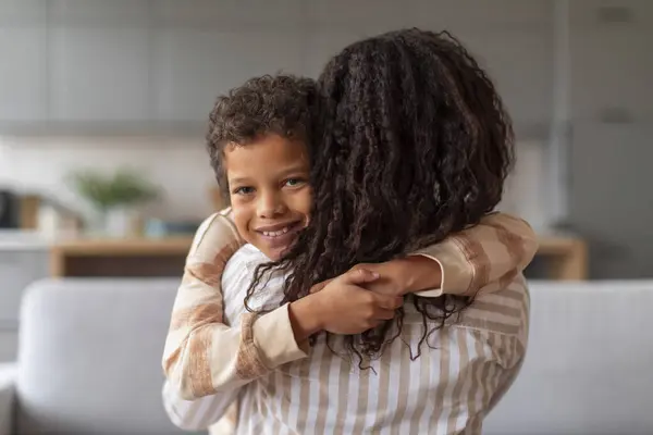 Usmívající Černoch Kudrnatými Vlasy Objímající Svou Milující Matku Doma Dívající — Stock fotografie
