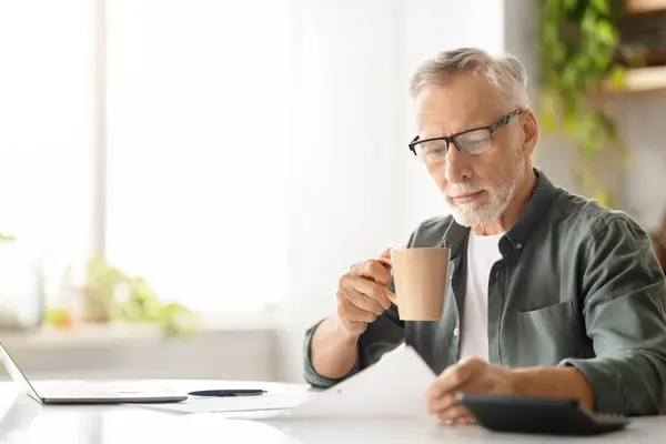 Konzentrierter Älterer Herr Gläsern Kaffee Trinkend Während Hellen Sonnenbeschienenen Homeoffice — Stockfoto
