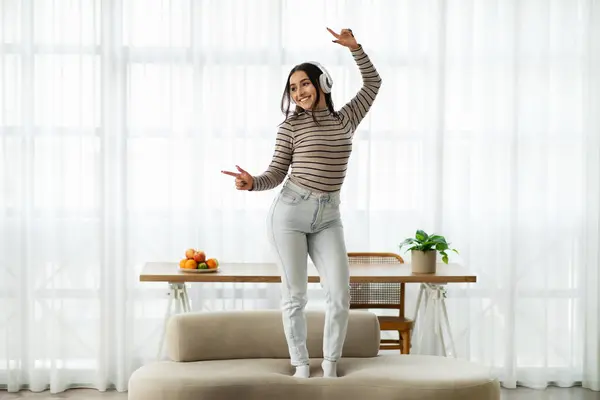 Vrolijke Jonge Vrouw Met Koptelefoon Dansend Een Beige Bank Haar — Stockfoto