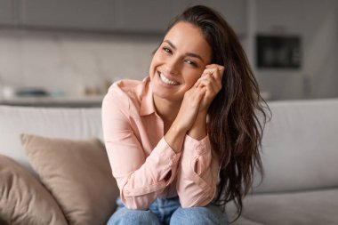 Radiant woman with contagious smile poses playfully, hands gently cradling her face, capturing moment of genuine happiness and effortless charm clipart