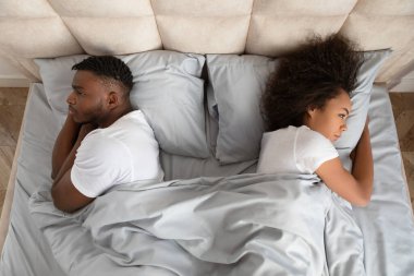 Evlilik Krizi. Siyahi genç çiftin yataklarında sırt sırta yatarken yatak odasının iç kısmında tartıştıktan sonra somurtması anlaşmazlık ve kayıtsızlıktan muzdarip olması. İlişki Sorunları