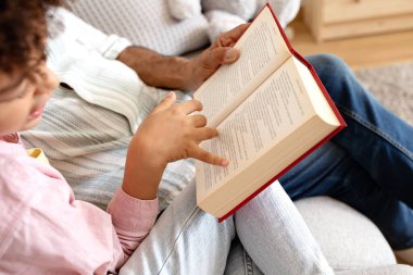 Son sınıf öğrencisiyle çocuğun evde kitap okurken çekilmiş bir fotoğrafı. Büyükbabanın torununu kucaklarken çocuk edebiyatının keyfini çıkardığı yakın plan. Nesiller arası bağlantı