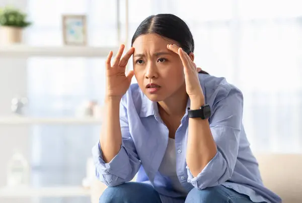 Distressed Young Asian Woman Sitting Couch Home Touching Her Head — Stock Photo, Image
