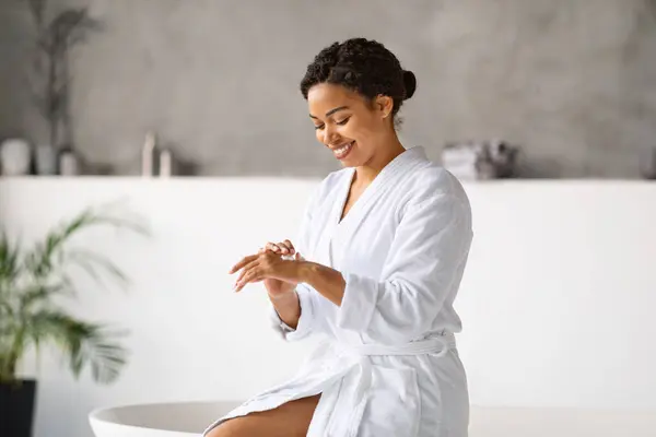 Mujer Negra Sonriente Aplicando Crema Manos Mientras Está Sentada Bañera — Foto de Stock