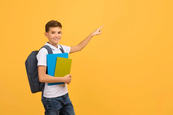 提供教育 微笑着少年男孩 带着书包带着快乐的男孩 带着书包带着指点 在黄色的背景上标明广告的免费位置 — 图库照片