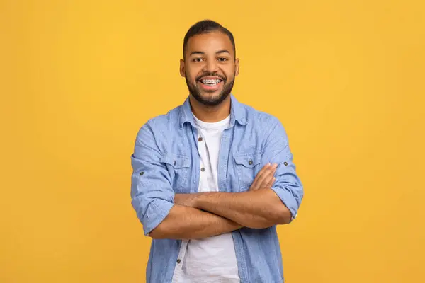 stock image Cheerful African American Guy Smiling To Camera, Posing With Crossed Hands While Standing Over Yellow Background, Studio Shot Of Happy Self-Confident Black Millennial Man Expressing Positive Emotions