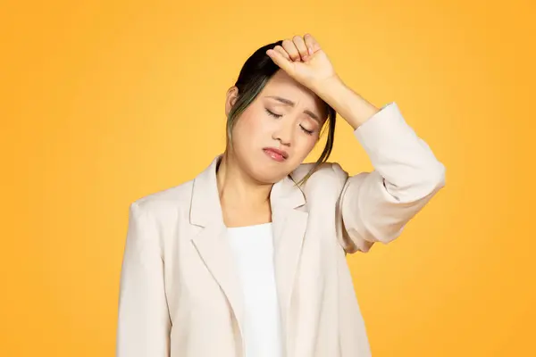 黄色いスタジオの背景に隔離された片頭痛に苦しむスーツで若い中国人女性を不幸にしました 健康問題 ストレス プレッシャー — ストック写真