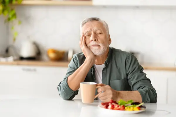 疲れた老人 手で頭を休ませ 朝食中に眠っている 疲労やリラクゼーションの瞬間を描いた上級紳士 家庭環境のキッチンテーブルに座って スペースをコピー — ストック写真