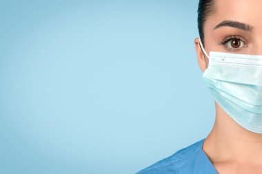 Cerrahi maske takan kadın hemşirelerin yakın çekimleri sağlık hizmetlerinde, gözlere odaklı, mavi arka planda, serbest alanda koruyucu önlemlerin önemini vurguluyor