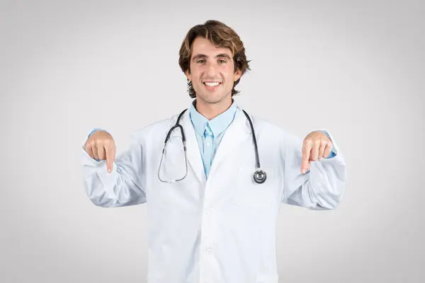 Médico Masculino Alegre Jaleco Branco Aponta Para Baixo Com Duas — Fotografia de Stock