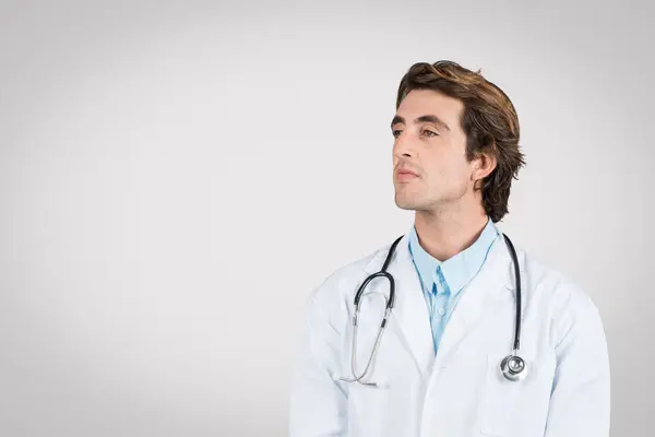 Médico Masculino Confiante Vestindo Casaco Branco Olhar Estetoscópio Espaço Livre — Fotografia de Stock