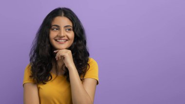 Meraklı, neşeli, kıvırcık saçlı, güzel bir doğulu kadın çenesine dokunuyor ve reklam için fotokopi odasına bakıyor. Güzel bir teklif, anlaşma, mor stüdyo geçmişi, afiş.