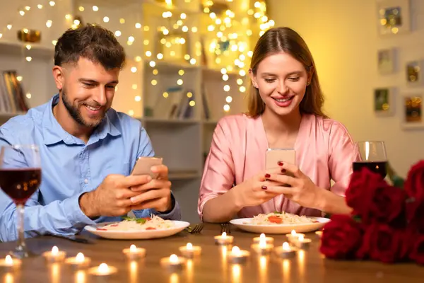 Jovem Mulher Jantar Romântico Ambos Sorridentes Absorvidos Seus Smartphones Com — Fotografia de Stock
