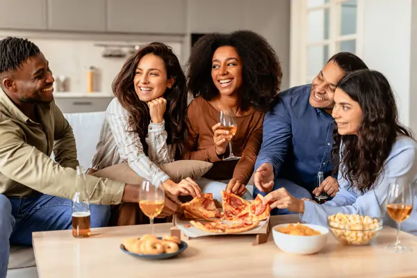 Students party. Diverse friends gathering for home dinner with beer and pizza, engaging in conversations over snacks and drinks, sharing laughter and joy in a comfortable kitchen indoor setting