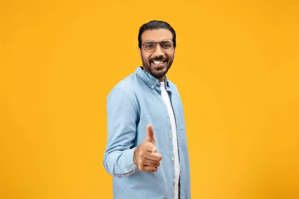 穿着斜纹棉布衬衫的和蔼可亲的男人竖起大拇指 对着摄像机笑着 在明亮的黄色背景下展示出一种赞许和积极向上的迹象 动机标志 — 图库照片