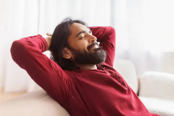 Relaxed Millennial Bearded Eastern Man Resting Couch Home Holding Arms — Stock Photo, Image