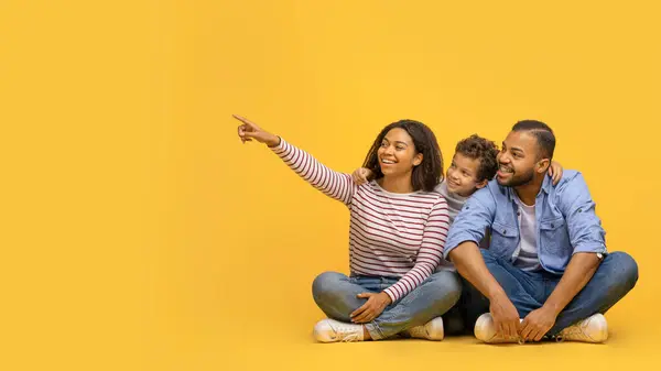 美しい若い幸せなアフリカ系アメリカ人家族の3つの床に座って黄色い背景のコピースペースの脇に立って あなたのデザインや広告のための自由な場所をデモンストレーション パノラマ — ストック写真