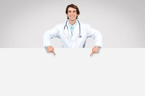 Veselý Mužský Lékař Stetoskopem Ukazuje Dolů Velký Prázdný Prapor Ideální — Stock fotografie