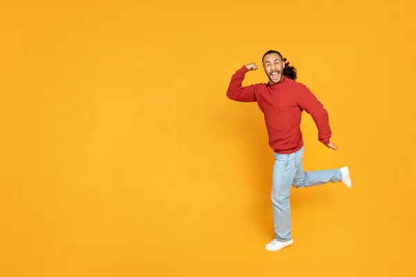 エキサイティングな若い男は イエローオレンジ色のスタジオの背景の上を走って 素晴らしいニュースを持っています 幸せな男は急いで 広告のためのコピースペースが付いている全長ショット — ストック写真