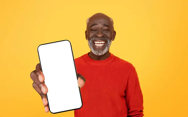 快乐的资深黑人男子 带着空白屏幕 面带微笑 黄色背景上穿着红色毛衣 非常适合展示应用程序或广告 — 图库照片