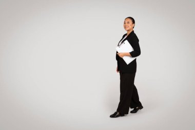 Gri arka planda, stüdyoda izole edilmiş, takım elbiseli, kendine güvenen Asyalı bir kadın. Başarılı iş, girişim, modern iş ve profesyonel yaşam tarzı