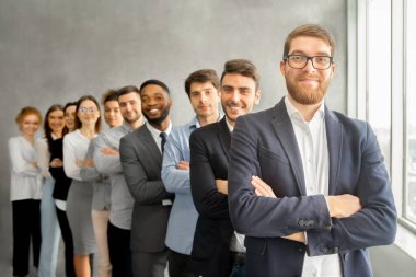 Mutlu iş ekibi patronla birlikte kollarını kavuşturup kameraya bakıyor.