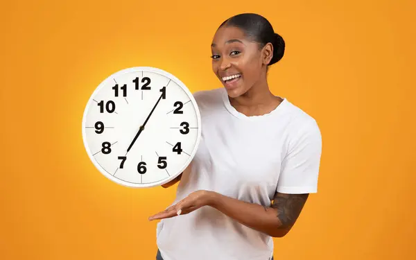 Lächelnde Afroamerikanerin Hält Große Uhr Zeigt Pünktlichkeit Und Terminmanagement Posiert — Stockfoto