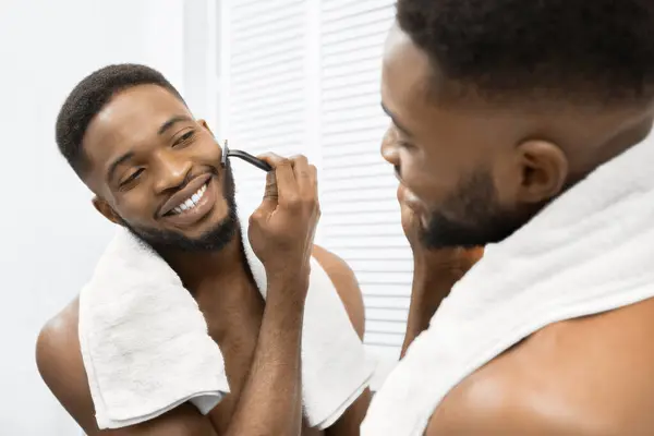 Hombre Afro Sonriente Con Torso Desnudo Afeitándose Barba Mirando Espejo —  Fotos de Stock