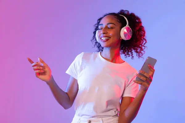 Parlak Siyahi Bayan Şık Kulaklıklarla Müzik Dinliyor Akıllı Telefon Tutuyor — Stok fotoğraf