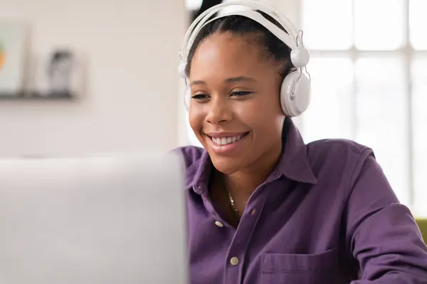 ラディアント黒人女性ティーン学生は ヘッドフォンを着て 彼女のコンピュータ画面で従事し 笑顔で 生産的なオンライン学習セッションを楽しんでいます — ストック写真