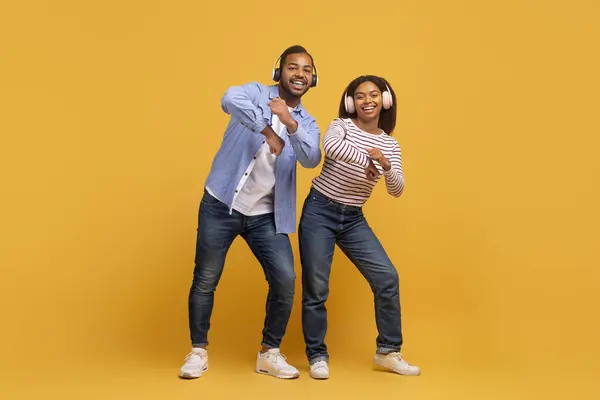Fröhliches Junges Schwarzes Paar Mit Trendigen Kopfhörern Die Auf Gelbem — Stockfoto