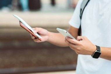 Bileti ve akıllı telefonu elinde tutan, tren saatlerini kontrol eden ya da uçağa binmeden önce internetten kontrol eden bir adam. Kapatın. Gezici mobil uygulama