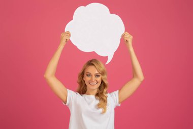 Düşünce kabarcığı. Genç çekici sarışın kadın pembe arka plana karşı duruyor, konuşma balonunu başının üstünde tutuyor ve kameraya gülümsüyor, indirimleri ve duyuruları destekliyor. Model