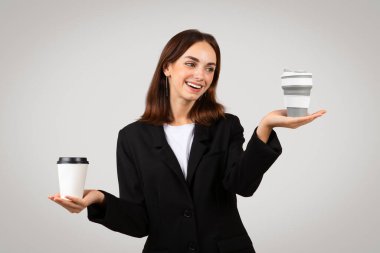 İş dünyasındaki ışıl ışıl beyaz bir kadın sevinçle iki kahve fincanını dengeliyor, biri elinde diğeri de avucunun üzerinde havada asılı duruyor, meşgul ama idare edilebilir bir yaşam tarzı olduğunu gösteriyor.