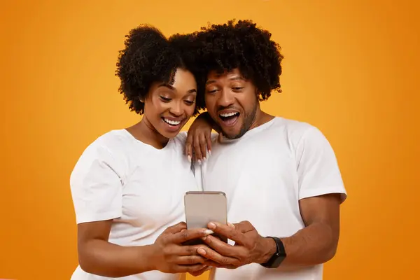 Удивительно Возбужденный Молодой Африканский Американец Мужчина Женщина Обнимаются Смотрят Смартфон — стоковое фото