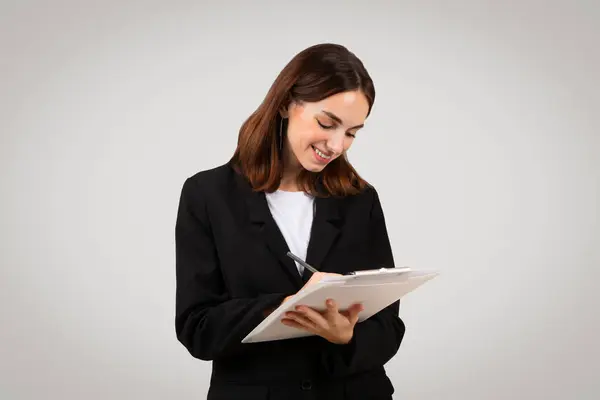 Uśmiechnięta Millenijna Kaukaska Bizneswoman Radośnie Zapisująca Notatki Schowku Prezentująca Moment — Zdjęcie stockowe