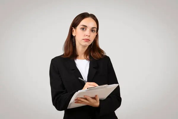 Serious Millennial Caucasian Businesswoman Formal Black Suit Writing Notes Clipboard — Stock Photo, Image