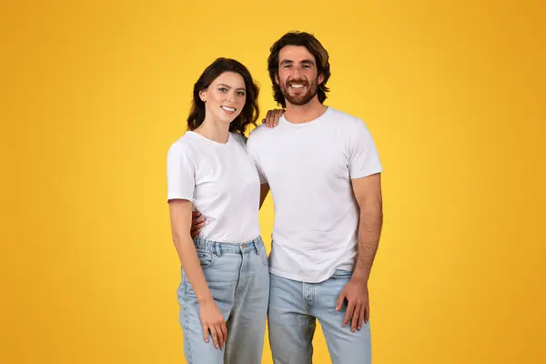 穿着白色T恤衫和蓝色牛仔裤站在一起 在明亮的黄色背景下微笑着 散发出一种随意平易近人的氛围 工作室 — 图库照片