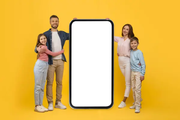 Happy Family Four Standing Big Smartphone Met Blanco Scherm Glimlachende — Stockfoto