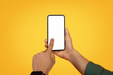 Beyaz beyaz ekran maketi olan akıllı telefonu tutan Afro-Amerikan bir adamın elleri. Siyah adam kullanıcısı boş ekran ile cep telefonuna dokunuyor, sarı arkaplan