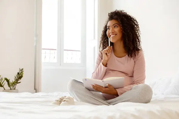 Mutlu Siyah Hamile Kadın Notepad Evde Yatakta Otururken Hayalperest Genç — Stok fotoğraf