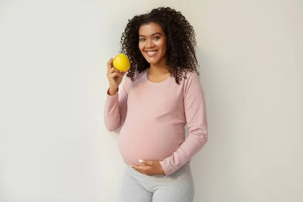 Güzel Siyah Hamile Kadın Elinde Elmayla Beyaz Duvar Arkasında Duruyor — Stok fotoğraf