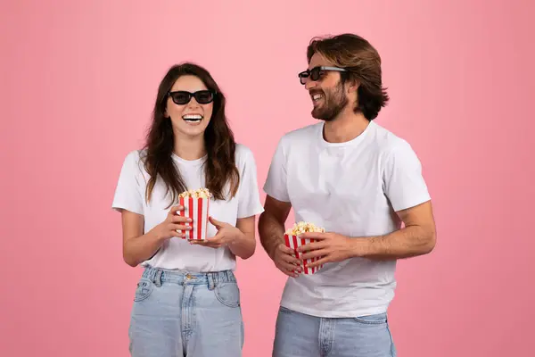 身穿3D眼镜 头戴红白相间条纹爆米花盒的欧洲女人和男人笑着 穿着粉色背景的白色T恤衫 一起欣赏电影之夜 — 图库照片