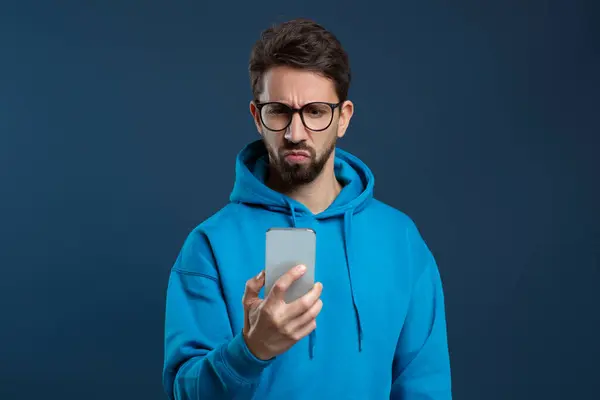Skeptical Man Wearing Glasses Looking Smartphone Screen Young Male Frowning — Stock Photo, Image